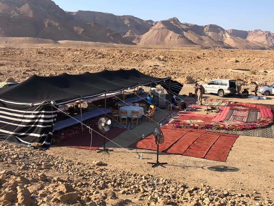 אוהל בדואי שחור עם שטיחים ומושבים במדבר