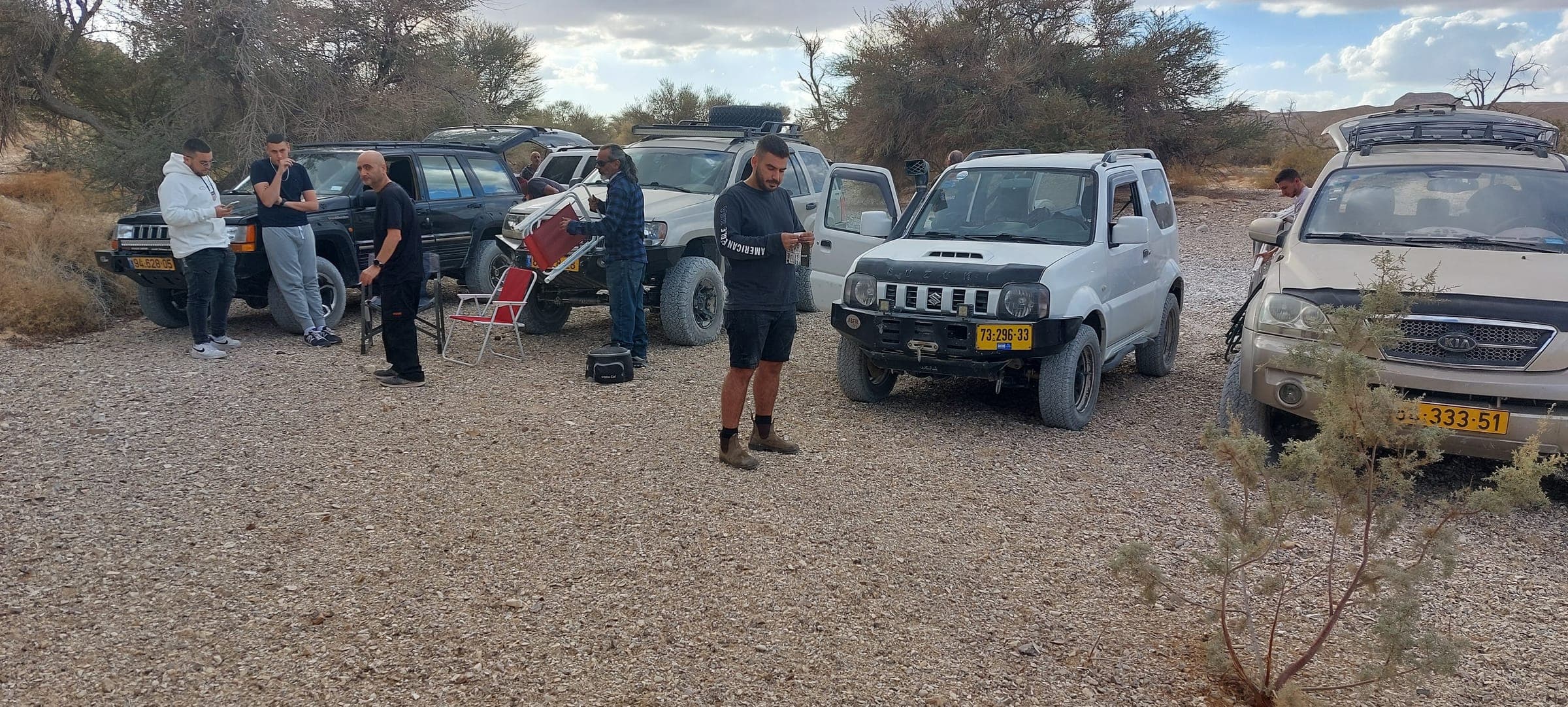 קבוצת מטיילים וג׳יפים בעצירת תצפית במדבר